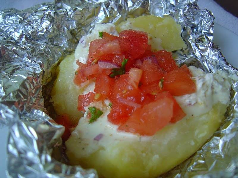 Ziemniaki pieczone w folii podane z twarożkiem i salsą z pomidorów.